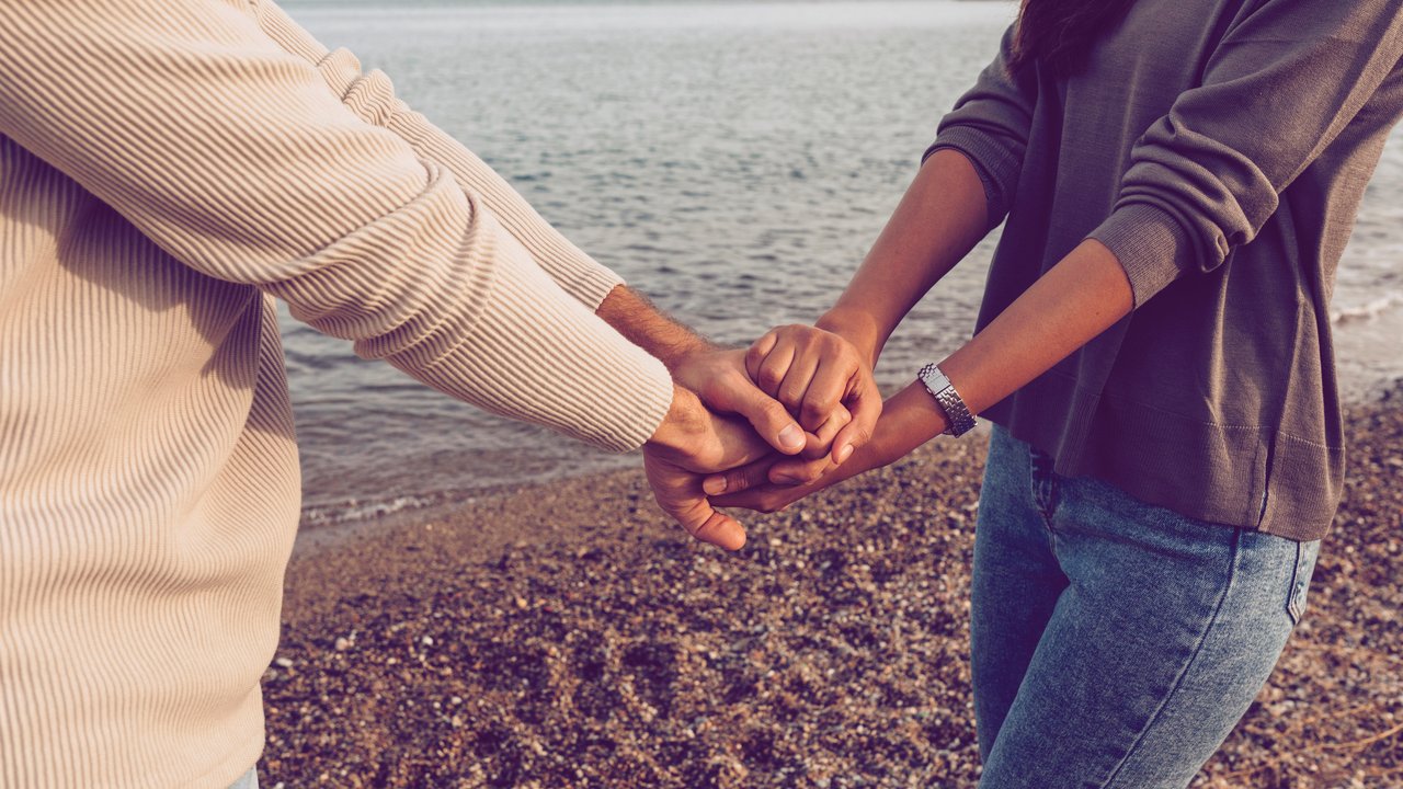 Girlfriend and boyfriend stacking hands while standing at beach model released Symbolfoto VABF04194