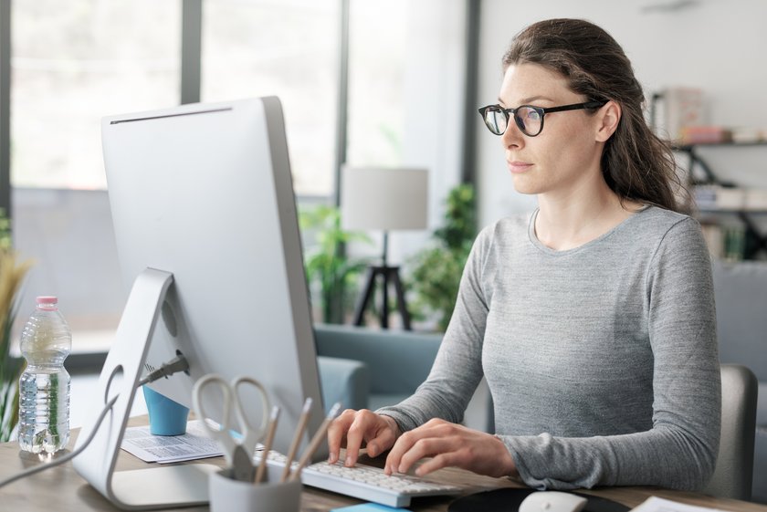 Professional woman sitting at desk and connecting with her computer, she is working from home Professional woman sitting at desk and connecting with her computer, she is working from home