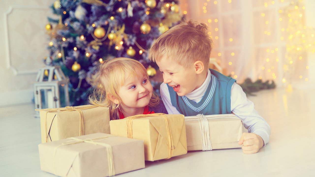 Little boy and girl opening christmas presents in decorated living room