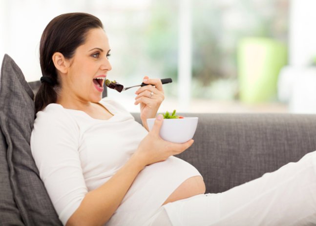Eisenmagel in der Schwangerschaft.Frau isst auf Sofa