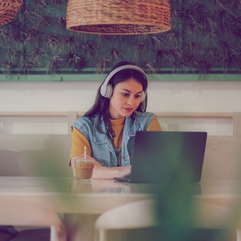 Frau mit Kopfhörer arbeitet in einem Café am Laptop Frau mit Kopfhörer arbeitet in einem Café am Laptop