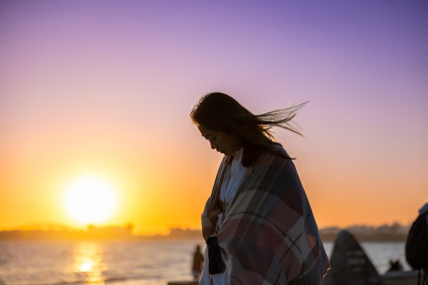 Frau steht am Strand bei Sonnenuntergang Frau steht am Strand bei Sonnenuntergang