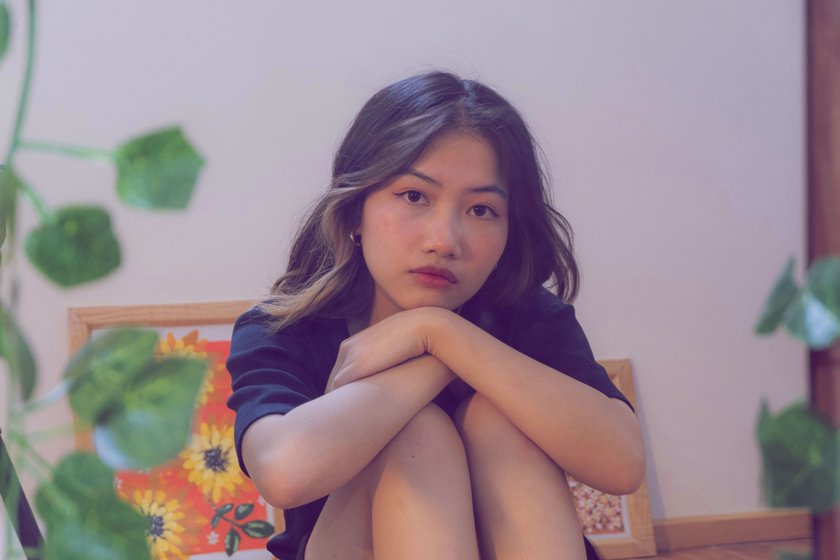 Frau, die traurig ihren Kopf auf Knie stützt Frau, die traurig ihren Kopf auf Knie stützt