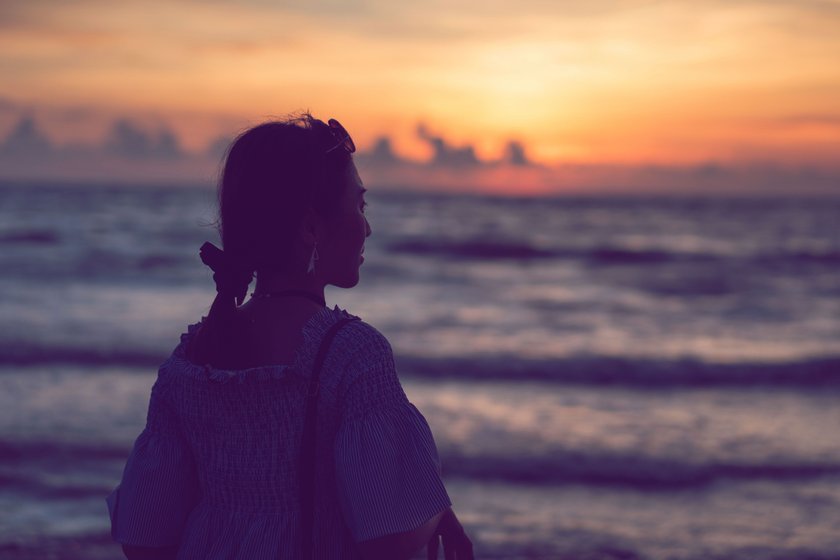 Frau steht vor dem Sonnenuntergang am Meer Frau steht vor dem Sonnenuntergang am Meer