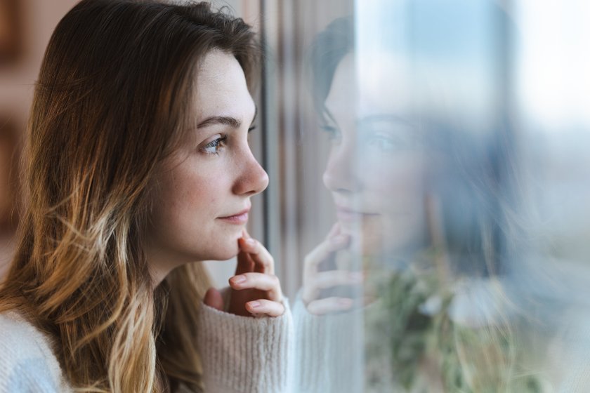 Nachdenkliche junge Frau schaut aus dem Fenster Nachdenkliche junge Frau schaut aus dem Fenster