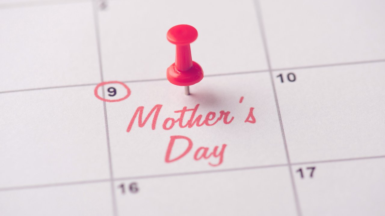 Happy mother's day concept. Cropped close up view photo of red pushpin attached to calendar with inscription mother's day
