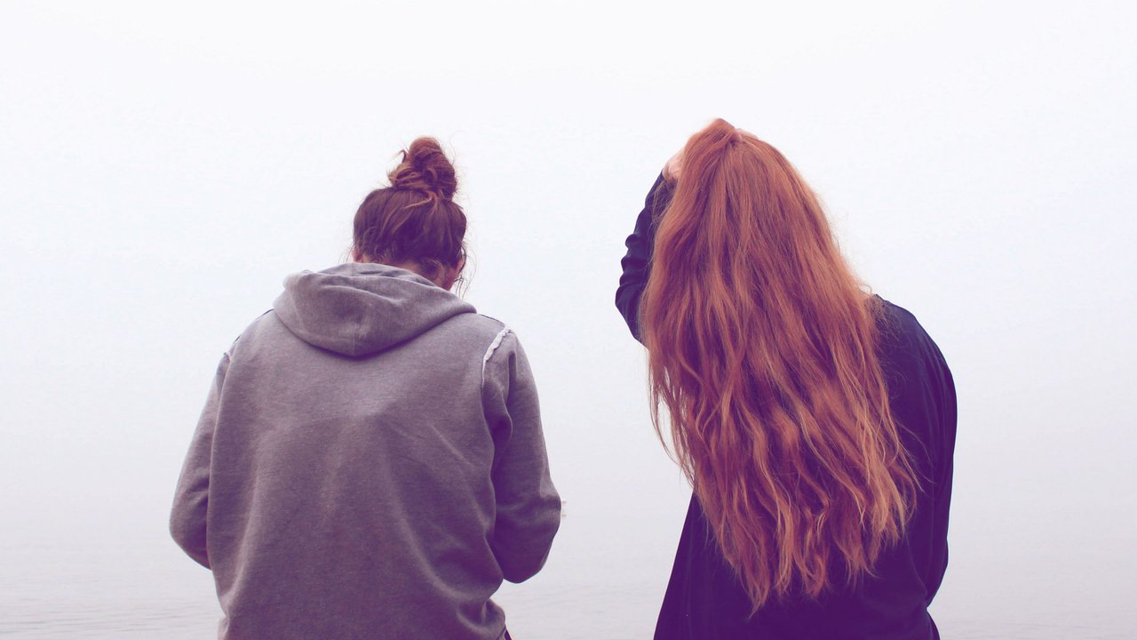 zwei Frauen, die an einem Steg sitzen und aufs Wasser schauen zwei Frauen, die an einem Steg sitzen und aufs Wasser schauen