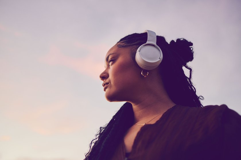 Frau mit Kopfhörern vor Himmel Frau mit Kopfhörern vor Himmel