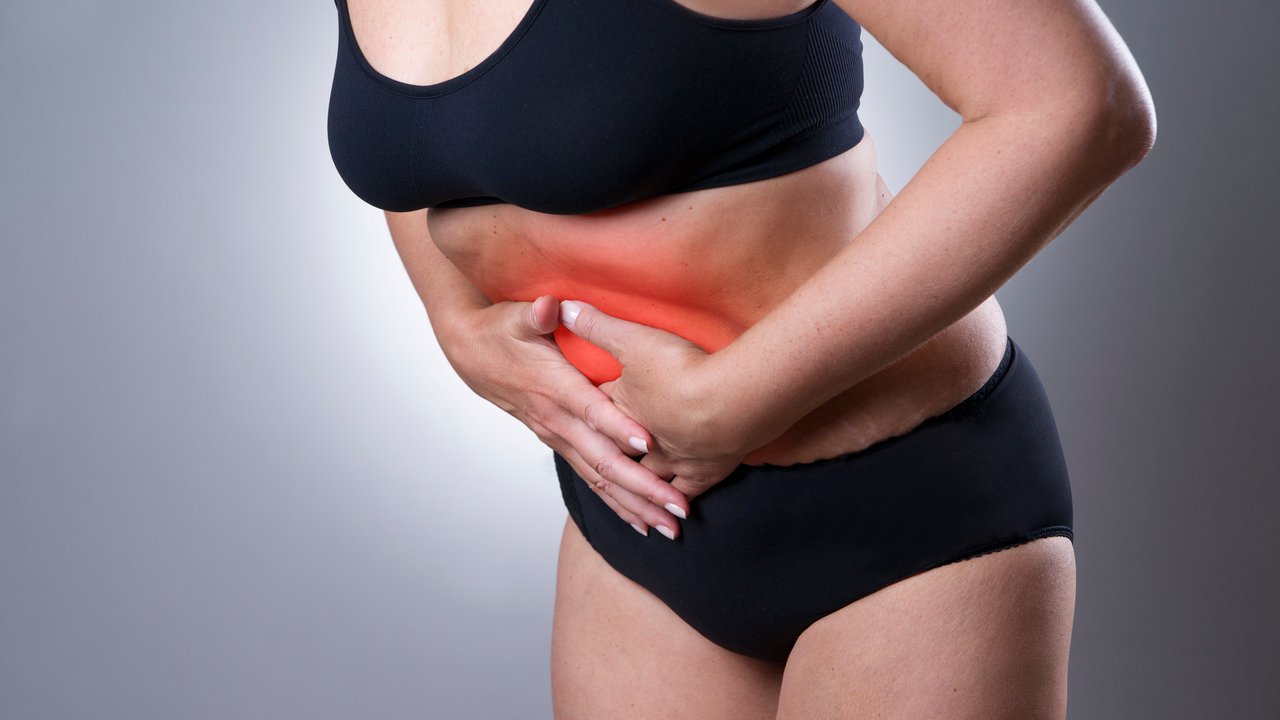 Woman with abdominal pain. Pain in the  human body on a gray background with red dot