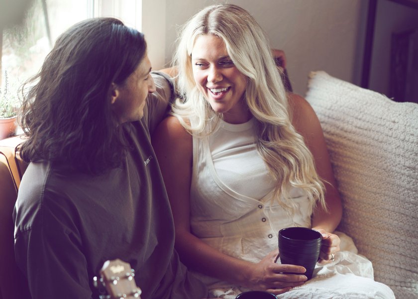 Paar, das auf Sofa sitzt und sich anlächelt Paar, das auf Sofa sitzt und sich anlächelt