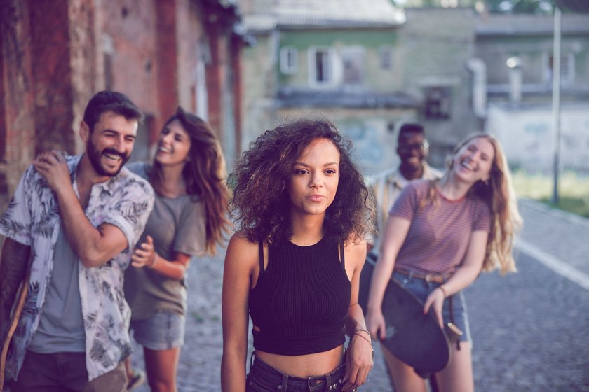 Frau, die etwas abseits von ihren Freund*innen steht Frau, die etwas abseits von ihren Freund*innen steht