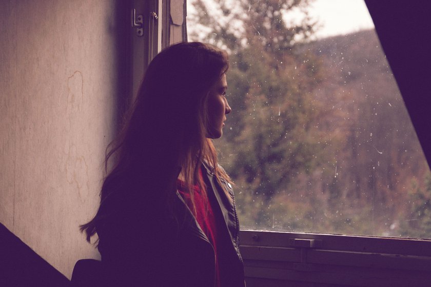 Frau schaut aus einem Fenster Frau schaut aus einem Fenster