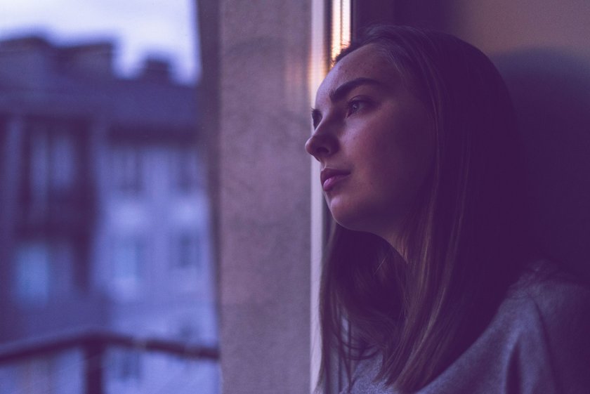 Frau, die traurig aus dem Fenster schaut Frau, die traurig aus dem Fenster schaut