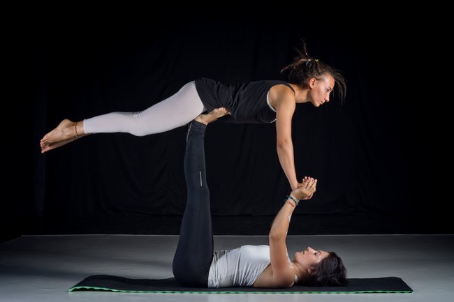 studio shot of two girls performing acro-yoga poses