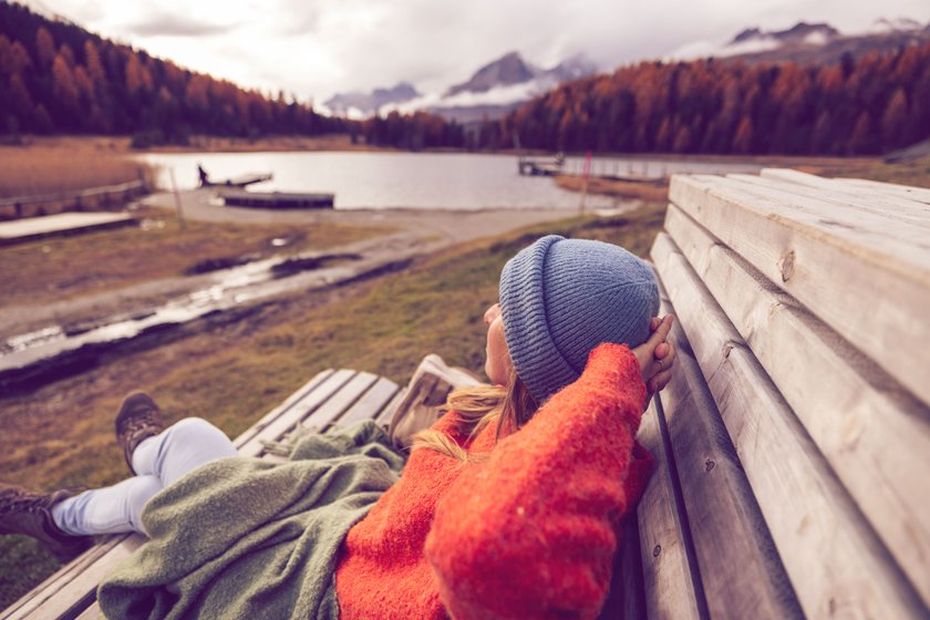 Frau genießt herbstliche Landschaft auf einer Bank Frau genießt herbstliche Landschaft auf einer Bank