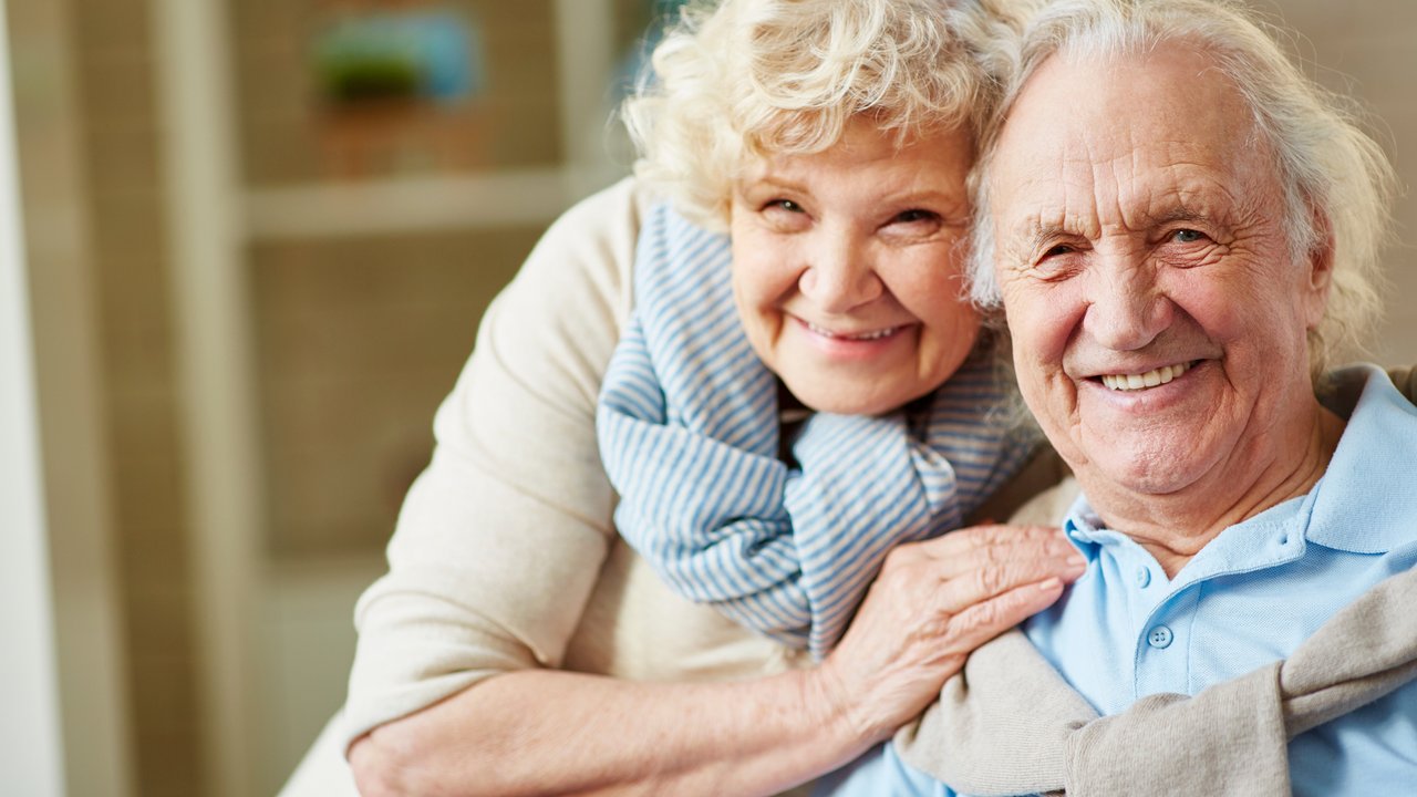 Affectionate elderly man and woman looking at camera
