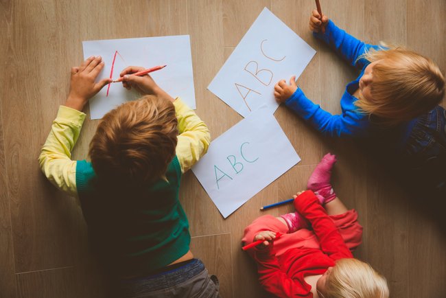 Kinder malen auf Papier auf dem Boden