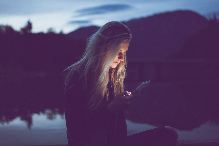 Frau, die im Dunkeln aufs Smartphone schaut Frau, die im Dunkeln aufs Smartphone schaut