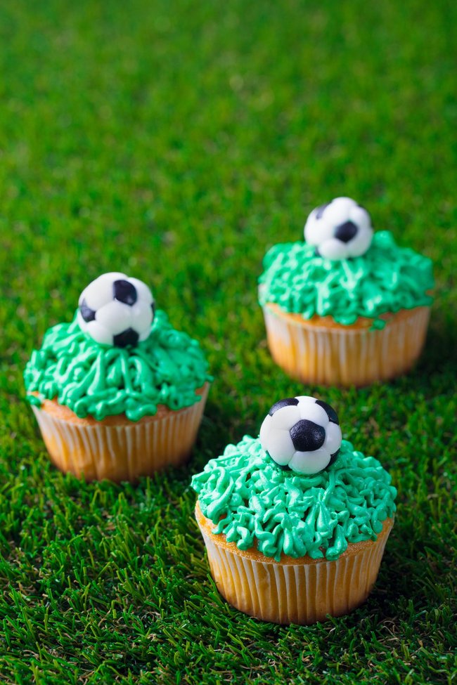Cupcake decorated with football ball on green grass background. Copy space. Cupcake decorated with football ball on green grass background. Copy space.
