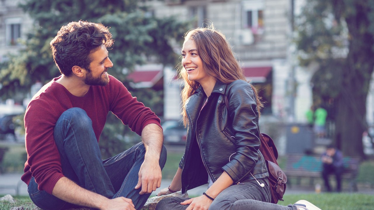 Mann und Frau, die im Park sitzen und reden Mann und Frau, die im Park sitzen und reden