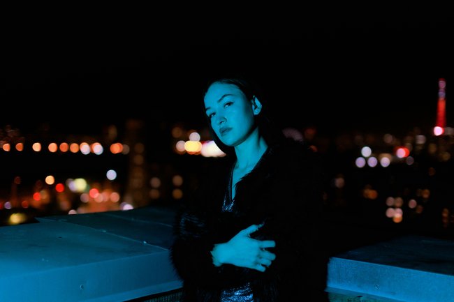 Frau, die auf einem Dach im Neonlicht steht Frau, die auf einem Dach im Neonlicht steht