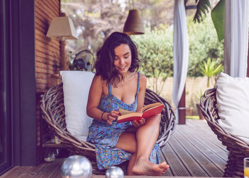 Frau, die auf Terrasse mit Buch entspannt