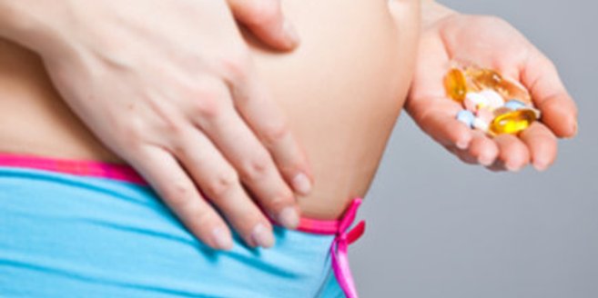 Schwangere Frau hält Tabletten vor dem Bauch Schwangere Frau hält Tabletten vor dem Bauch