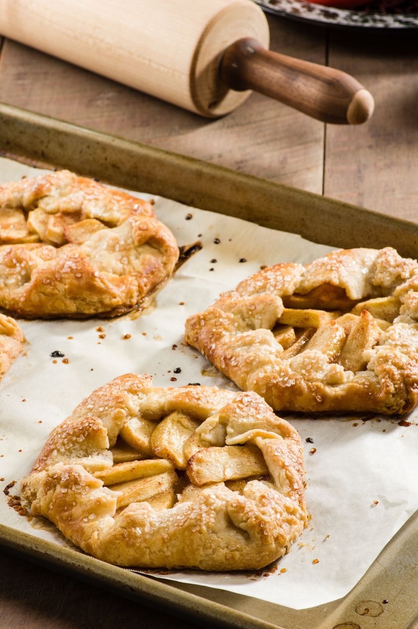 Tray of freshly baked apple tarts with a rolling pin