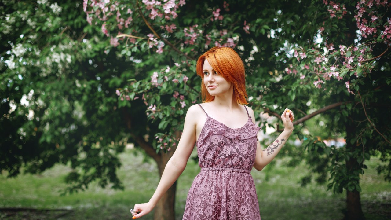 Young redhead woman near blossoming spring tree, natural beauty