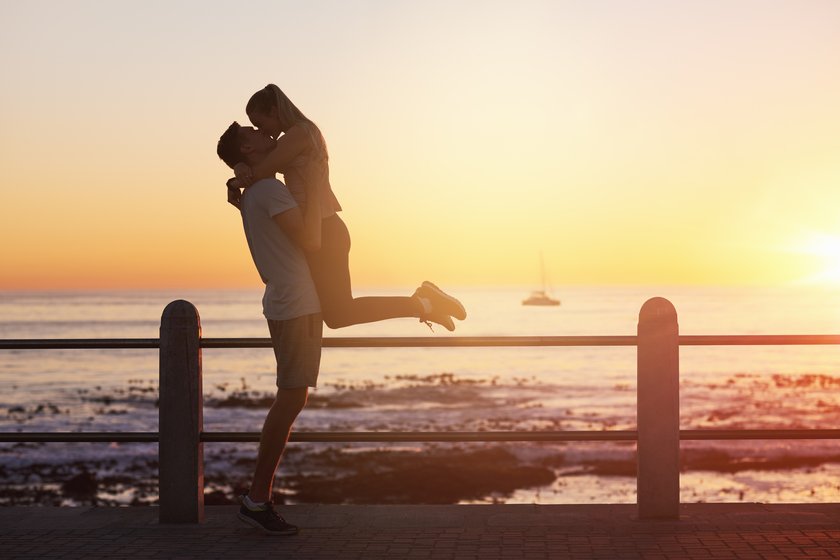 Paar küsst sich innig am Meer während die Sonne untergeht