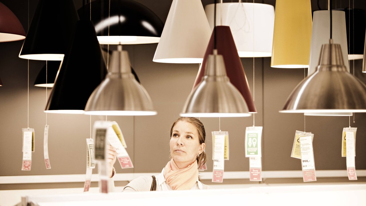Eine Frau sucht bei IKEA nach einer Lampe.