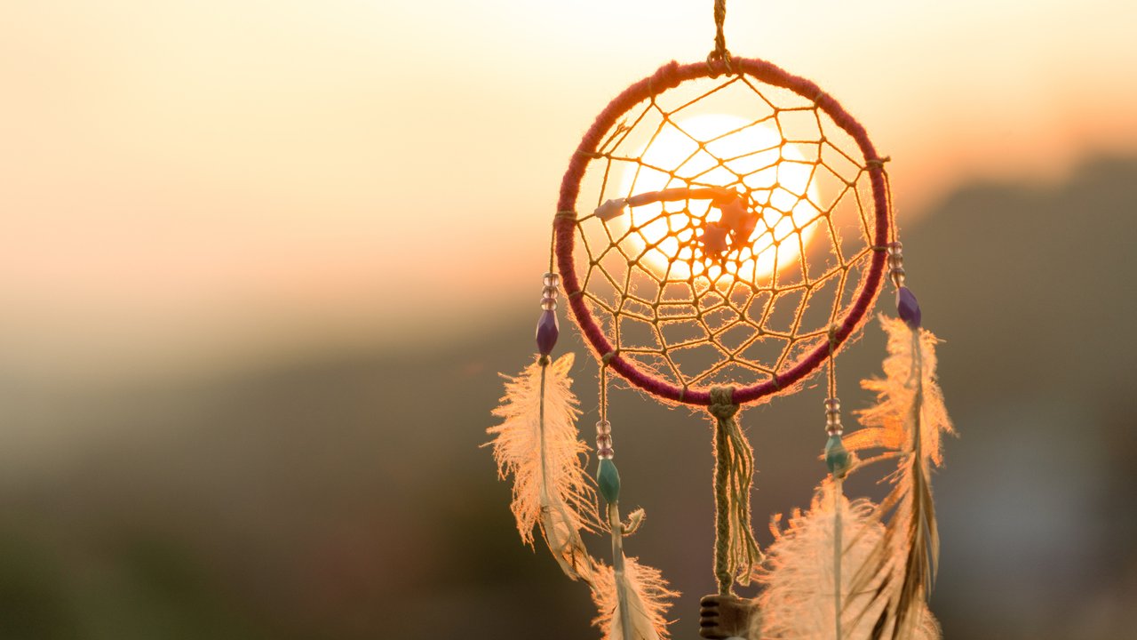 Dream cathcher amulet with sunset in background.Dream catcher is a handmade willow hoop woven to a web or literally  includes such features as feathers and beads