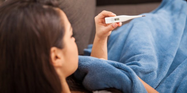Temoeraturkurve: Frau liest ihre Temperatur von einem Thermometer ab. Temoeraturkurve: Frau liest ihre Temperatur von einem Thermometer ab.