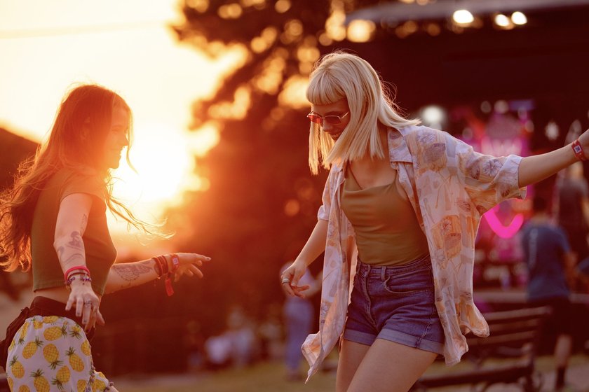 Happy women having fun while dancing on an outdoor music festival at sunset.