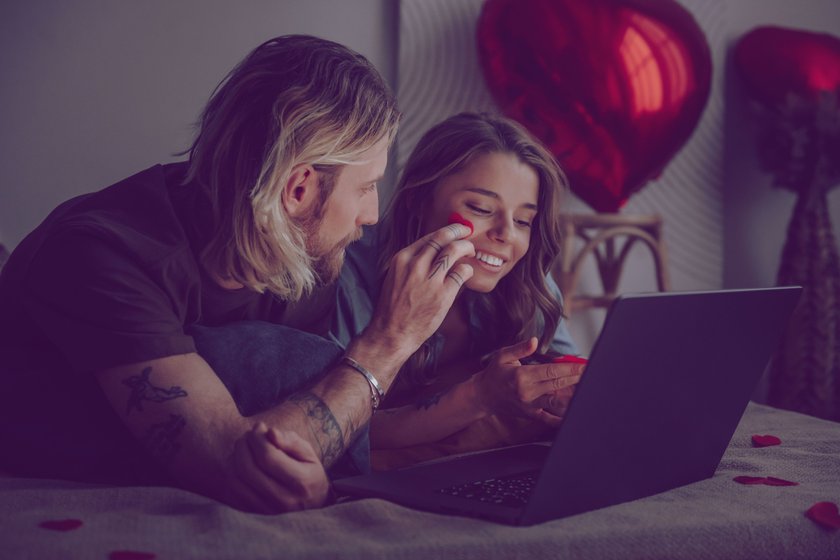 Paar liegt im Bett vor dem Laptop