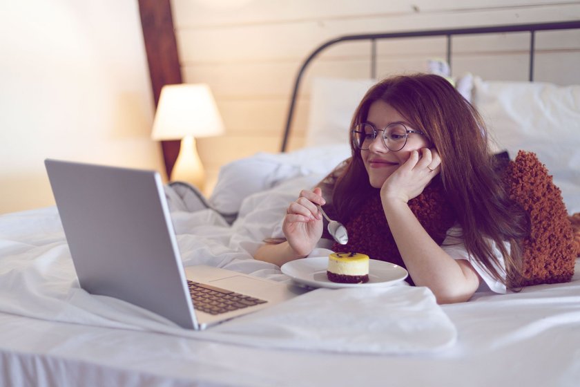 Frau schaut Serie auf Laptop in Bett