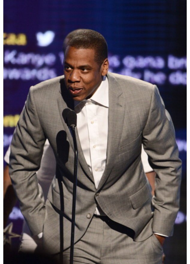 Jay-Z in einem grauen Anzug am Mikro. Jay-Z in einem grauen Anzug am Mikro.