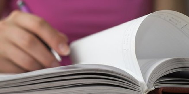 Frau nimmt Kalender, um ihre Schwangerschaftswoche zu berechnen Frau nimmt Kalender, um ihre Schwangerschaftswoche zu berechnen