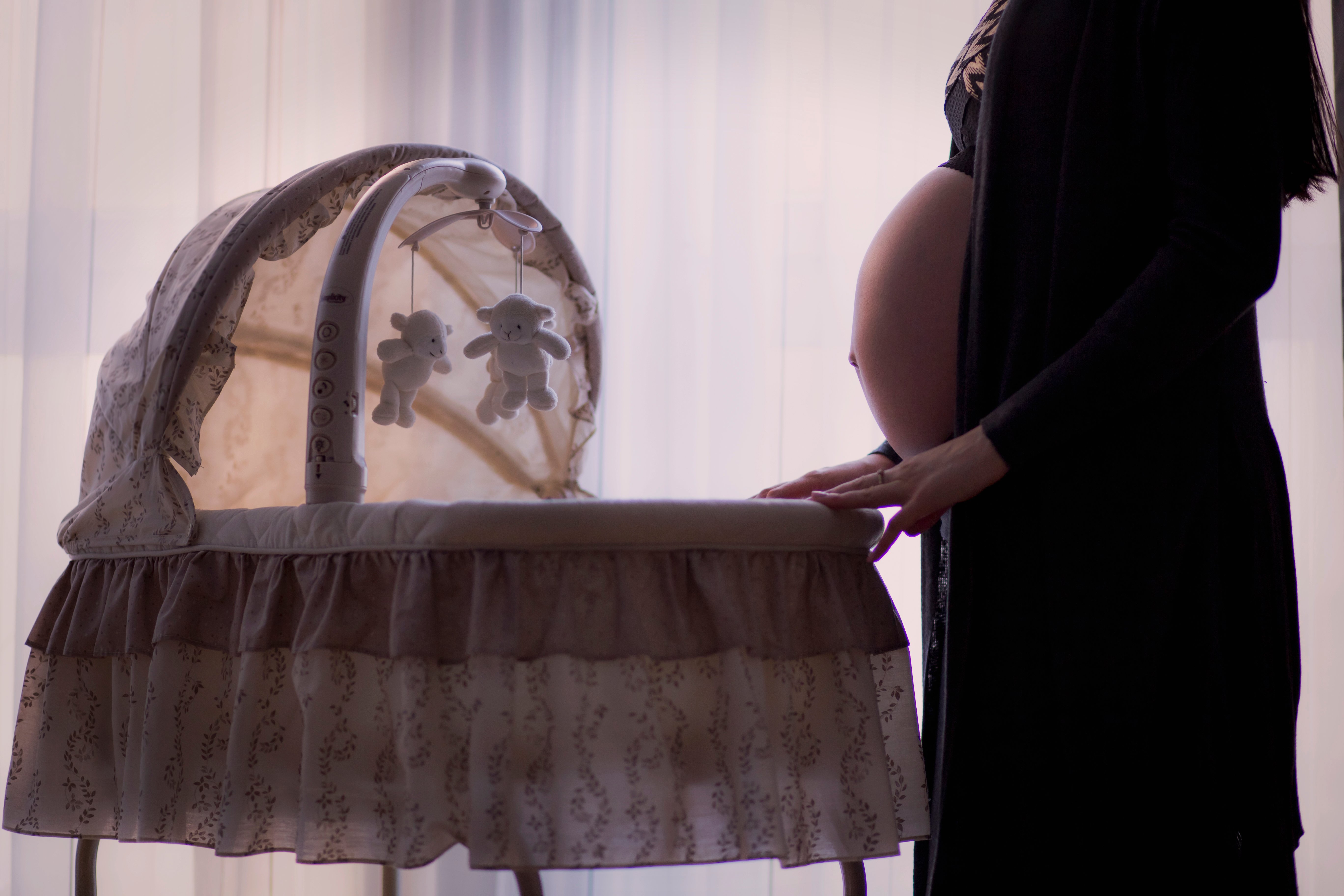 Schwangere steht vor Kinderbett