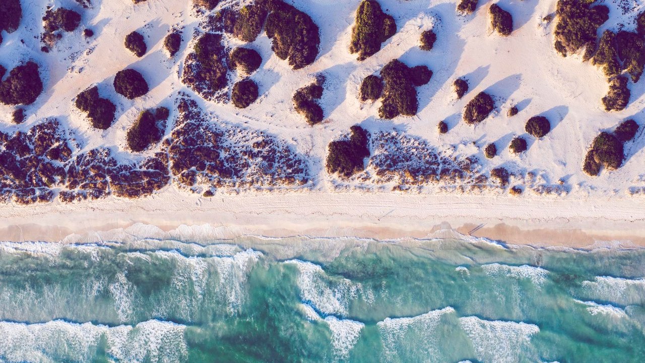 drone shot of beach Platja des trenc, island Mallorca, Balearic Islands, Spain at sunset, waves are rolling in