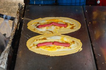 Khanom Tokyo wird dieser thailändische Straßen-Snack genannt. Die herzhafte Variante ist ein Hot Dog mit Ei im Pfannkuchenteig. Khanom Tokyo wird dieser thailändische Straßen-Snack genannt. Die herzhafte Variante ist ein Hot Dog mit Ei im Pfannkuchenteig.