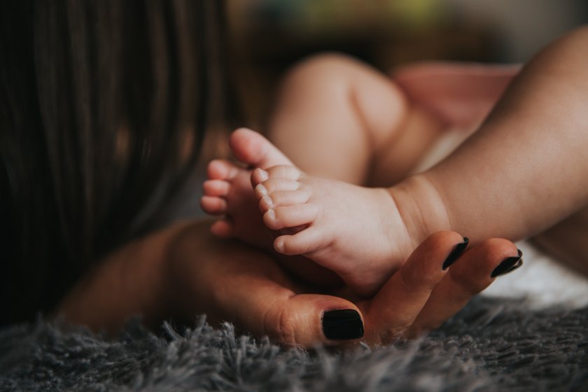 Mama hält die kleinen Füße ihres Babys in den Händen
