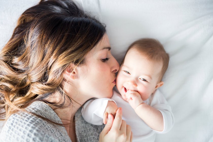 Frau küsst Baby auf die Wange, Kind lacht