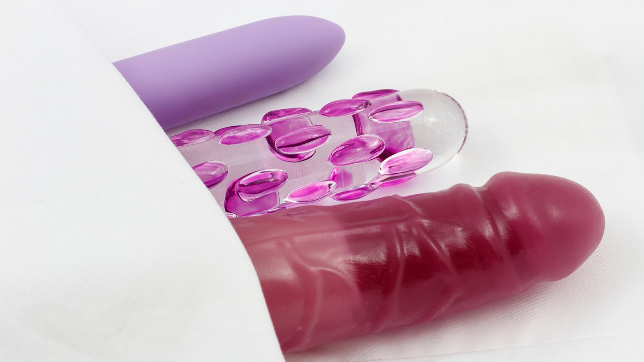 Sex Toys - Glass dildo and vibrators in bed