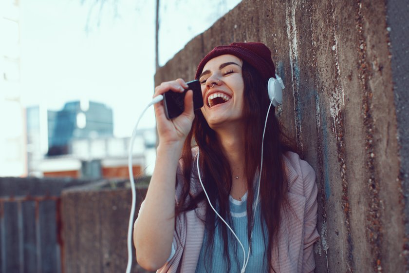 Frau hört Musik mit Kopfhörern und singt