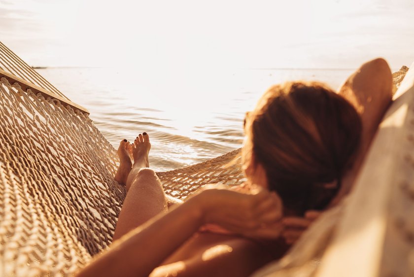 Eine Frau entspannt sich in einer Hängematte an einem Strand