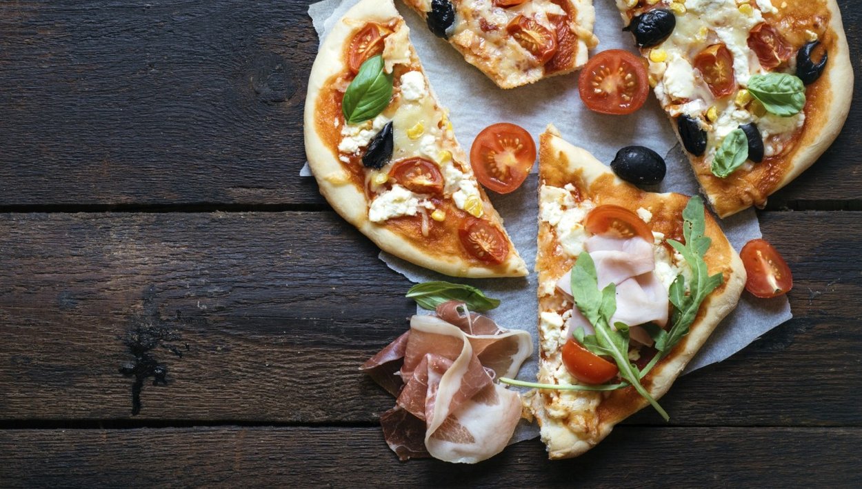 Slices of mini pizza variety served on wooden board and background,from above and blank space Slices of mini pizza variety served on wooden board and background,from above and blank space
