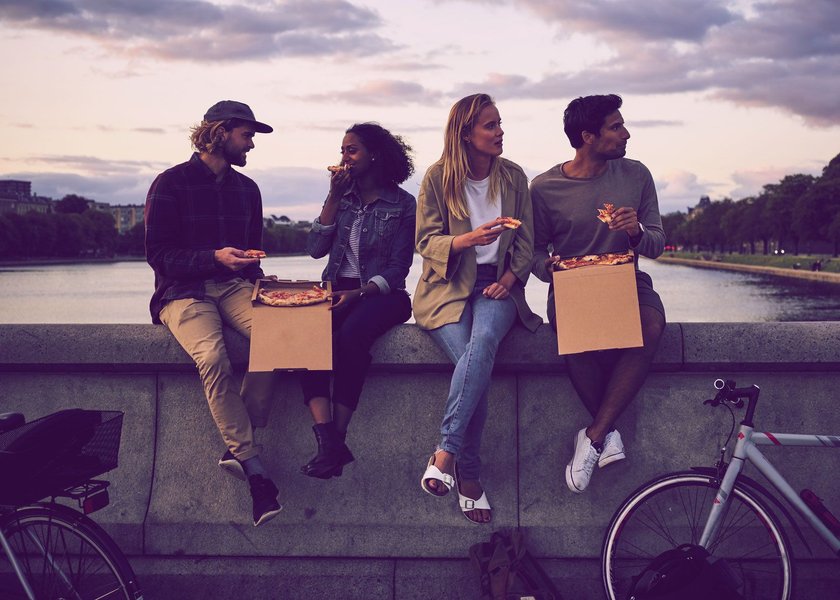 Freunde essen Pizza am Wasser