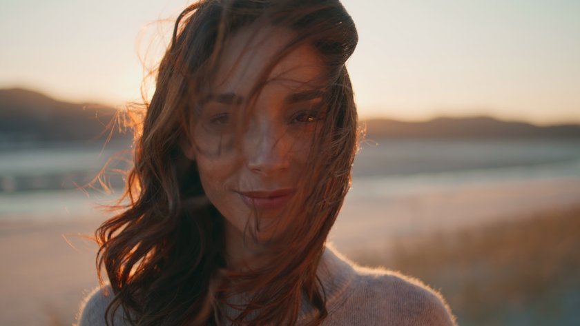 Eine Frau genießt am Strand im Sommer den Aufgang der Sonne