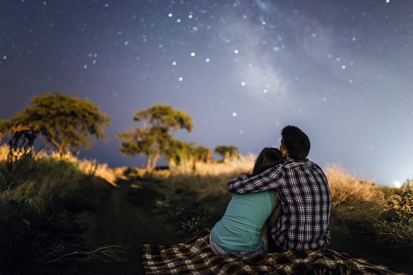Paar sitzt auf einer Decke und schaut in den Sternenhimmel